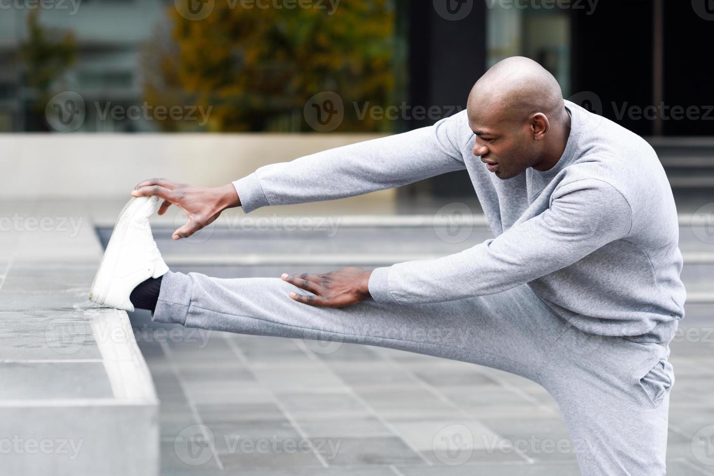 homem negro fazendo alongamento antes de correr em meio urbano foto