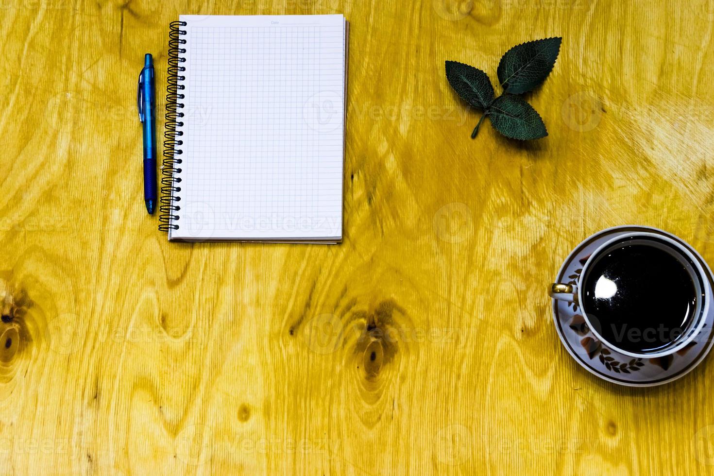 xícara de café e notebook aberto em fundo de madeira foto