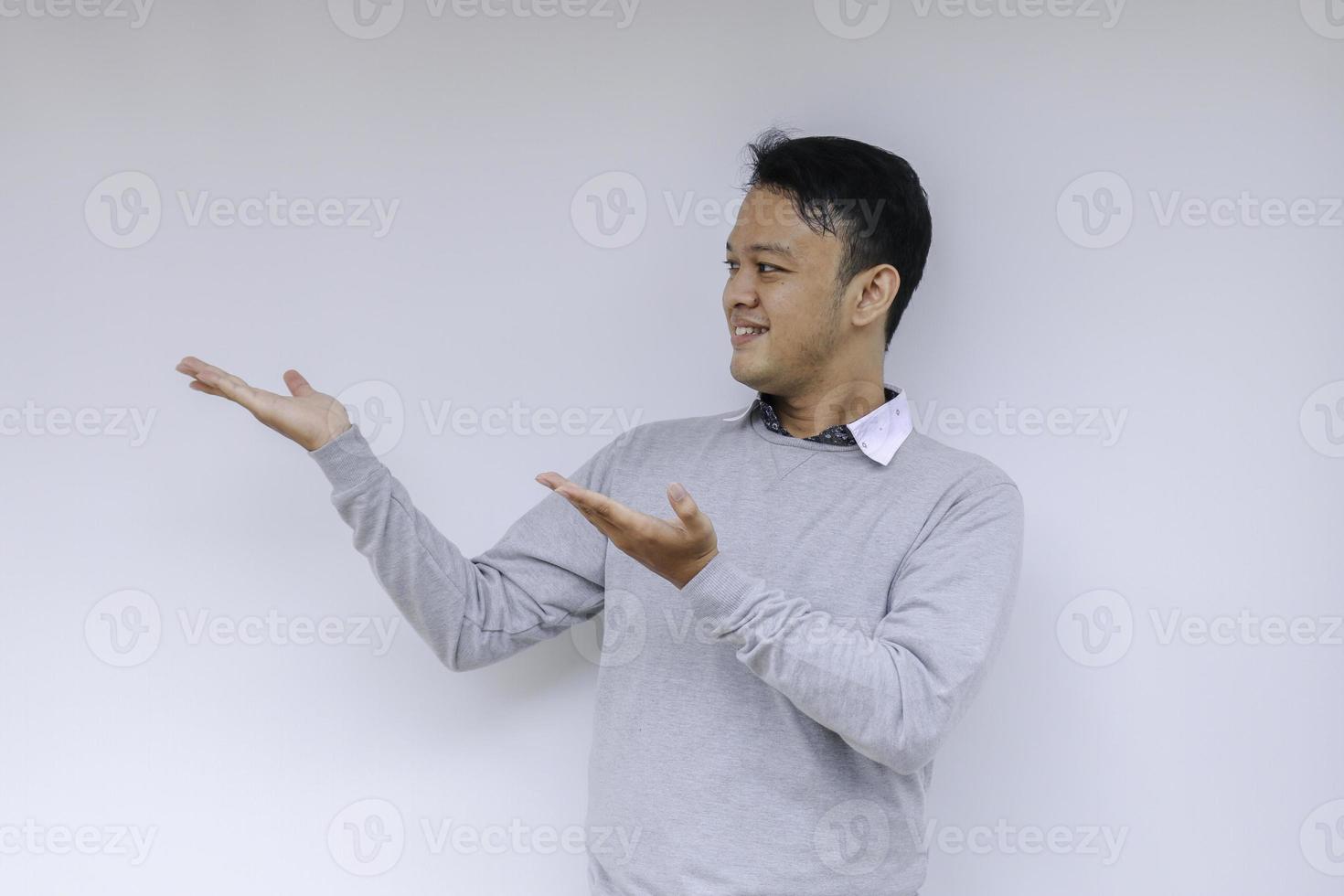 sorriso de jovem asiático de camisa branca com ponto de mão no espaço vazio foto