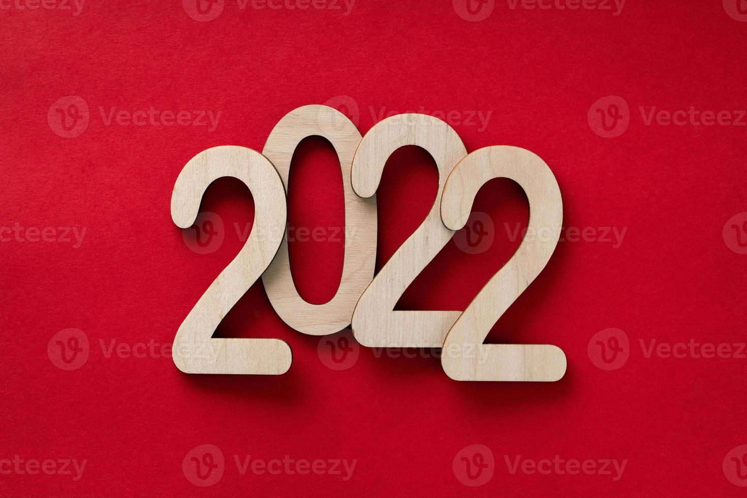 Números de madeira de 2022 anos sobre o fundo de papel vermelho com sombras foto