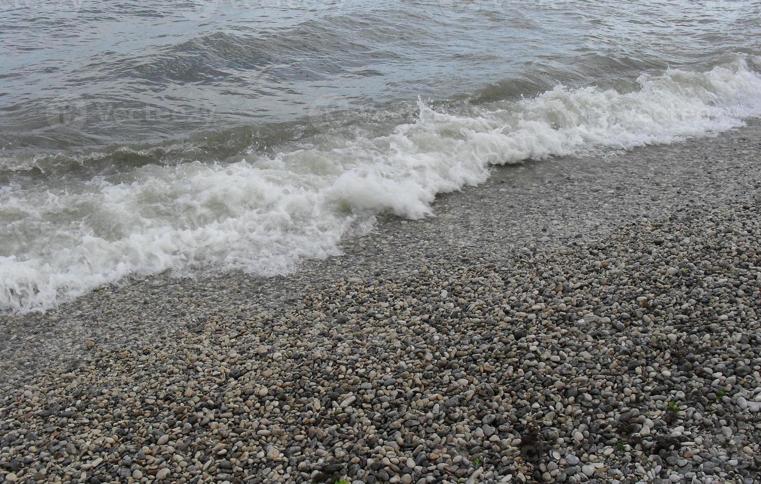 onda do mar com espuma na praia com seixos. plano de fundo, banner, verão, viagens foto
