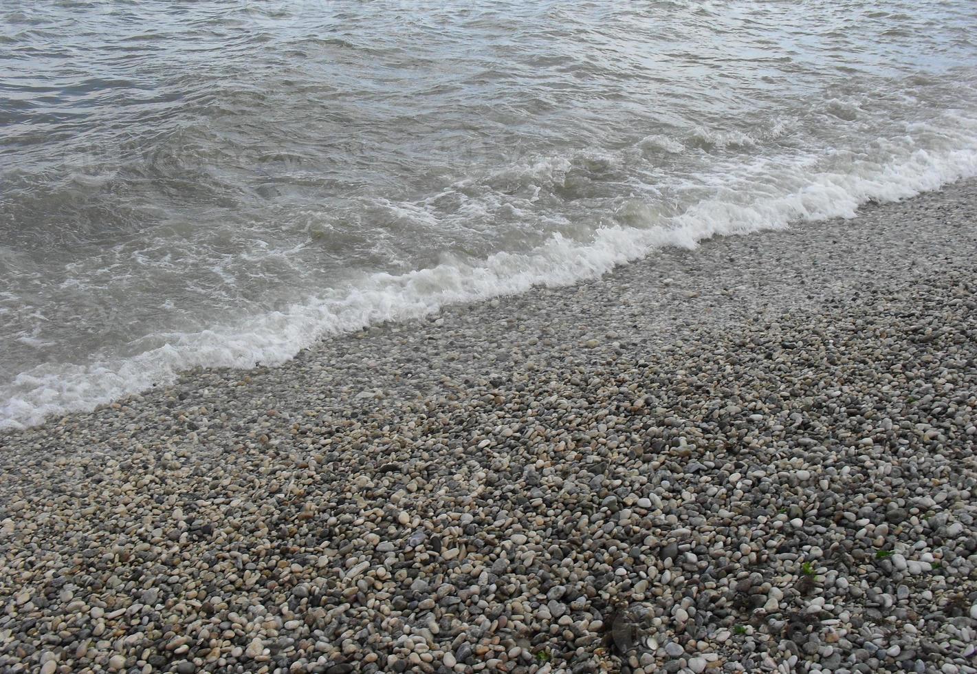 onda do mar com espuma na praia com seixos. plano de fundo, banner, verão, viagens foto