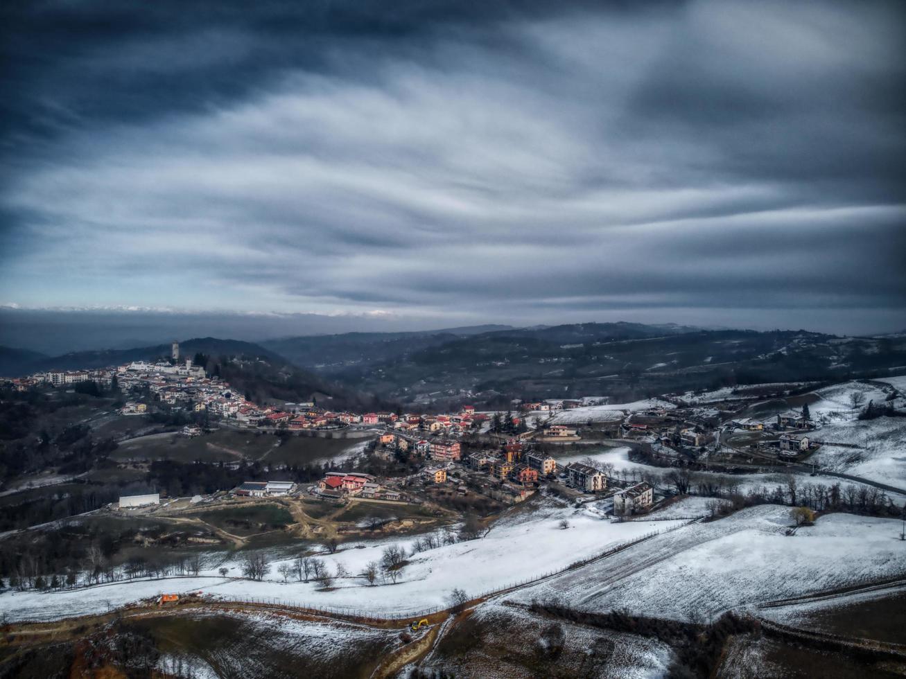 a vila de murazzano com sua torre e a vila na langhe piemontesa na província de cuneo, em um dia de inverno coberto de neve foto