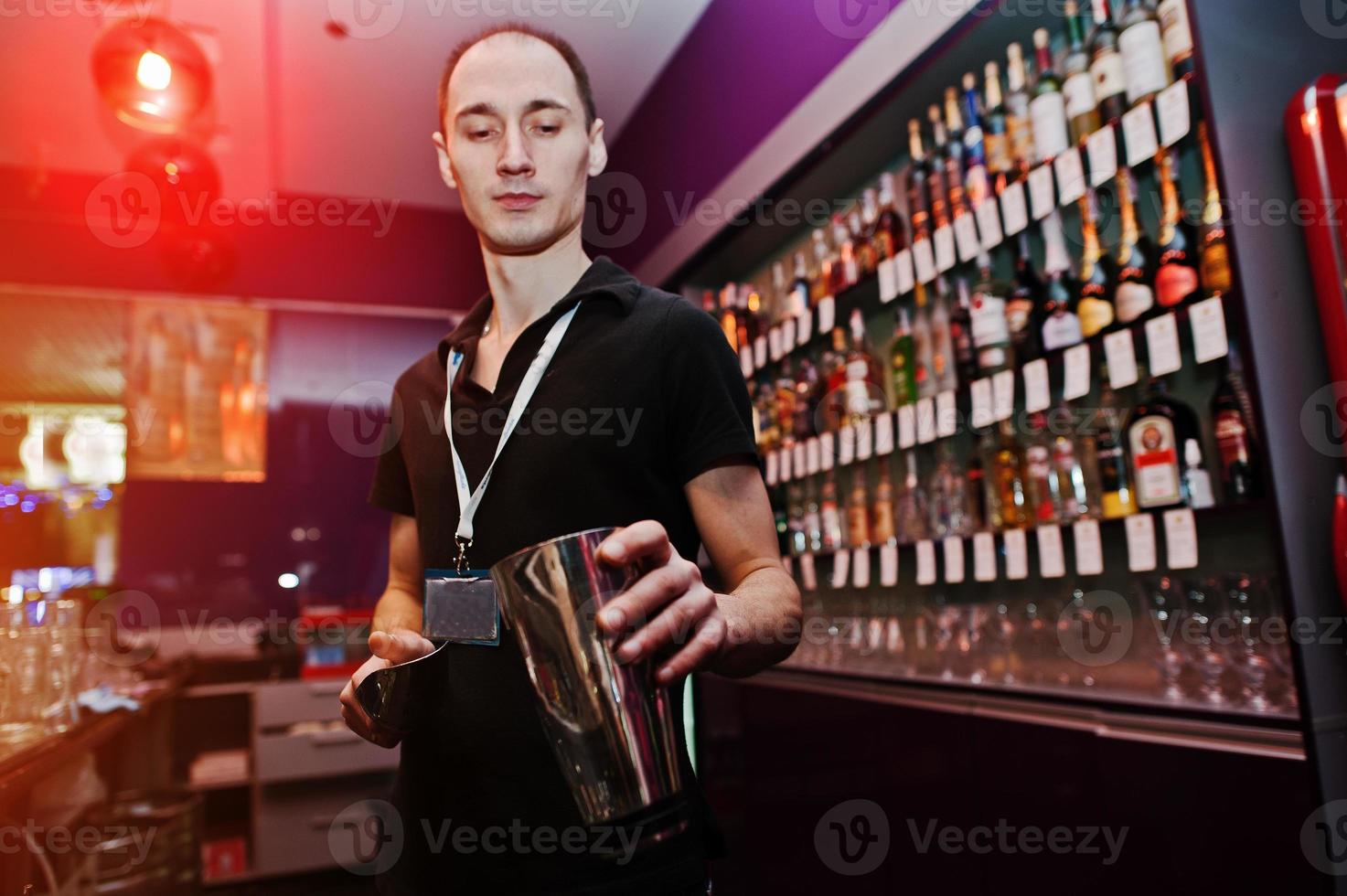 jovem barman joga gelo no bar foto