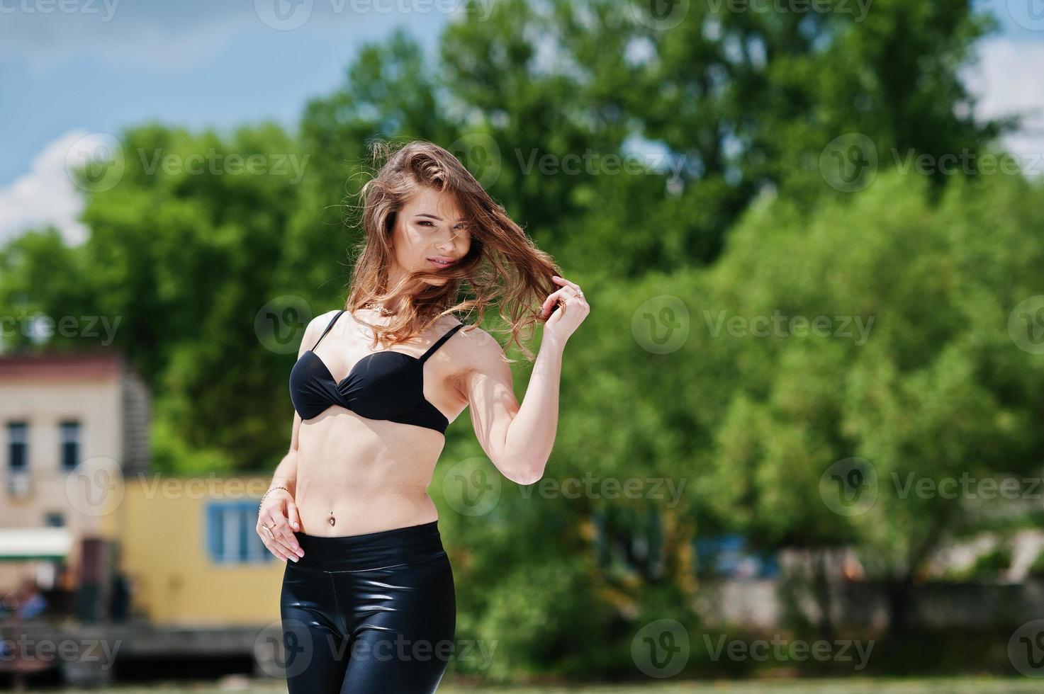 retrato do modelo de menina morena sexy linda em sutiã preto e calças de couro apertadas foto