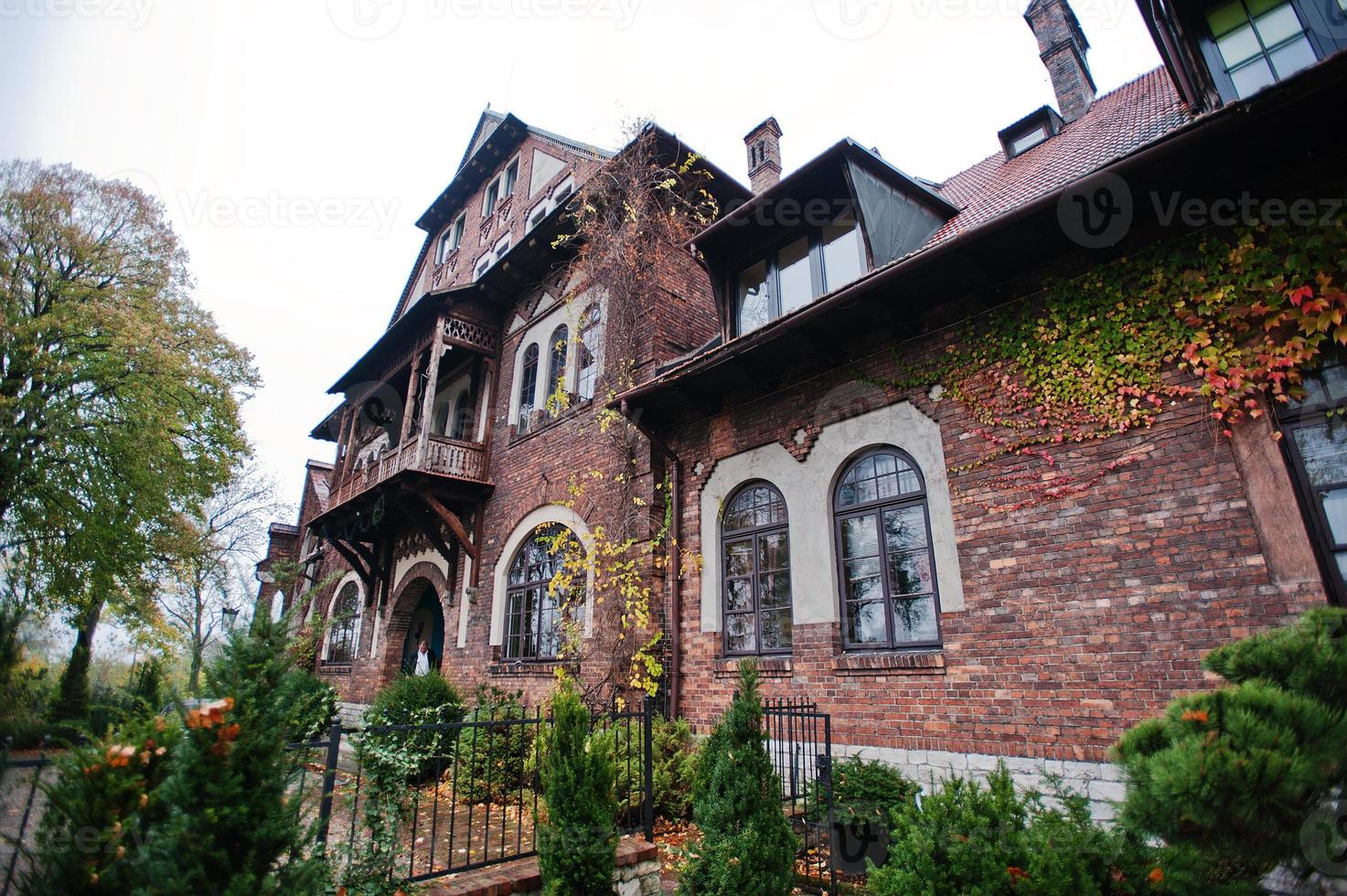 antiga mansão mística de tijolos abandonados. edifício gótico no outono foto