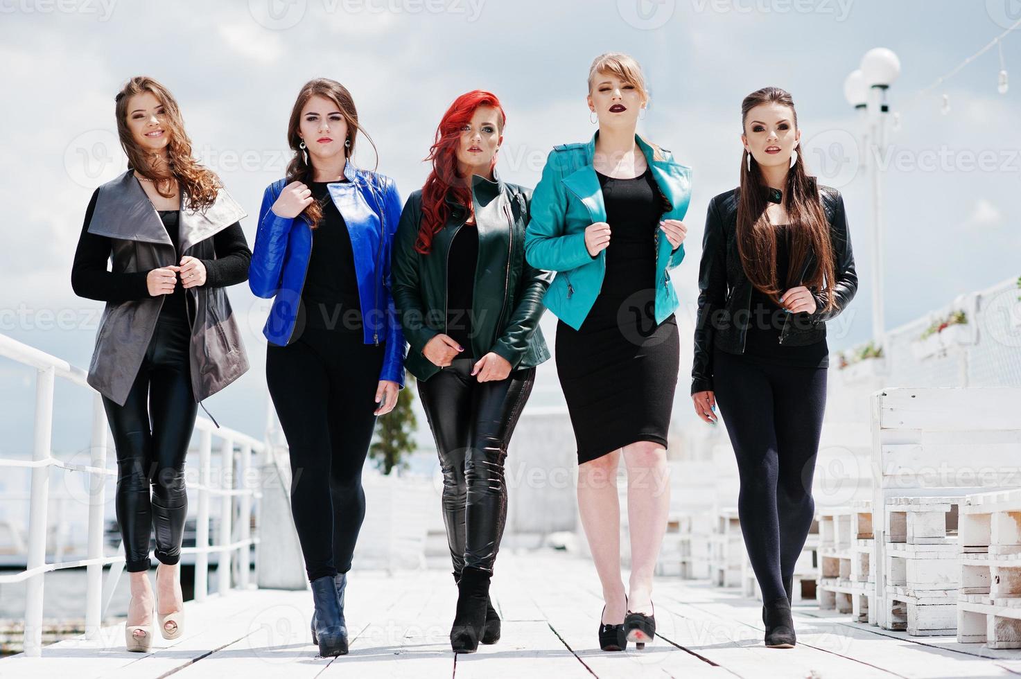 cinco modelos de meninas bonitas em jaquetas de couro posando no cais. foto
