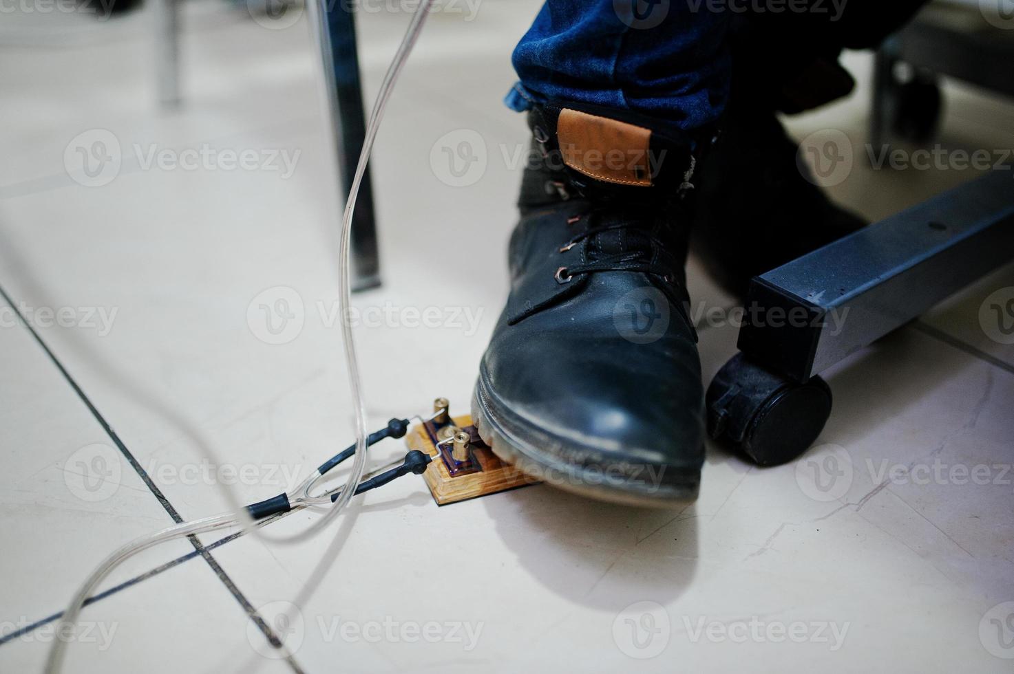 pé no pedal do mestre de tatuagem na máquina de tatuagem foto