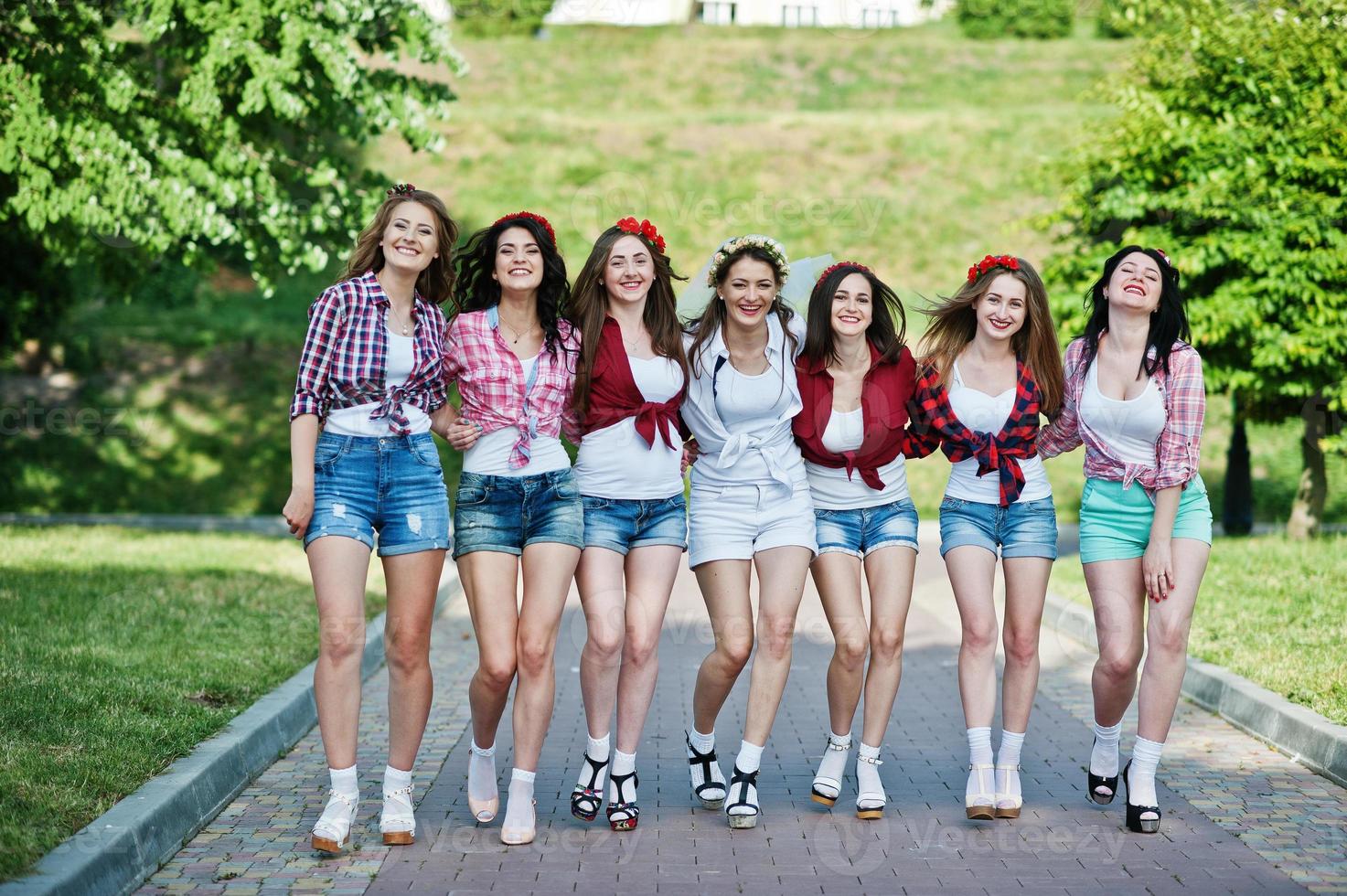 sete garotas felizes e sexy em shorts curtos posaram e se divertindo na estrada no parque na despedida de solteira foto