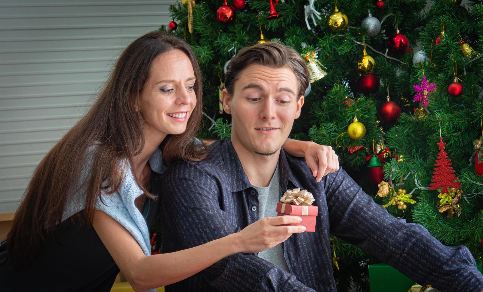 na imagem conceitual, presentes de natal. mulher branca caucasiana apresenta um presente em uma caixa vermelha para um jovem ou amante. feliz quando recebeu um presente foto