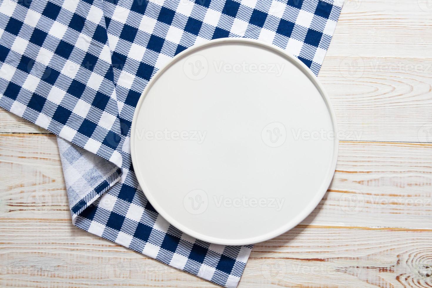 bandeja de prato branco vazio na toalha de mesa na vista superior da mesa de madeira foto