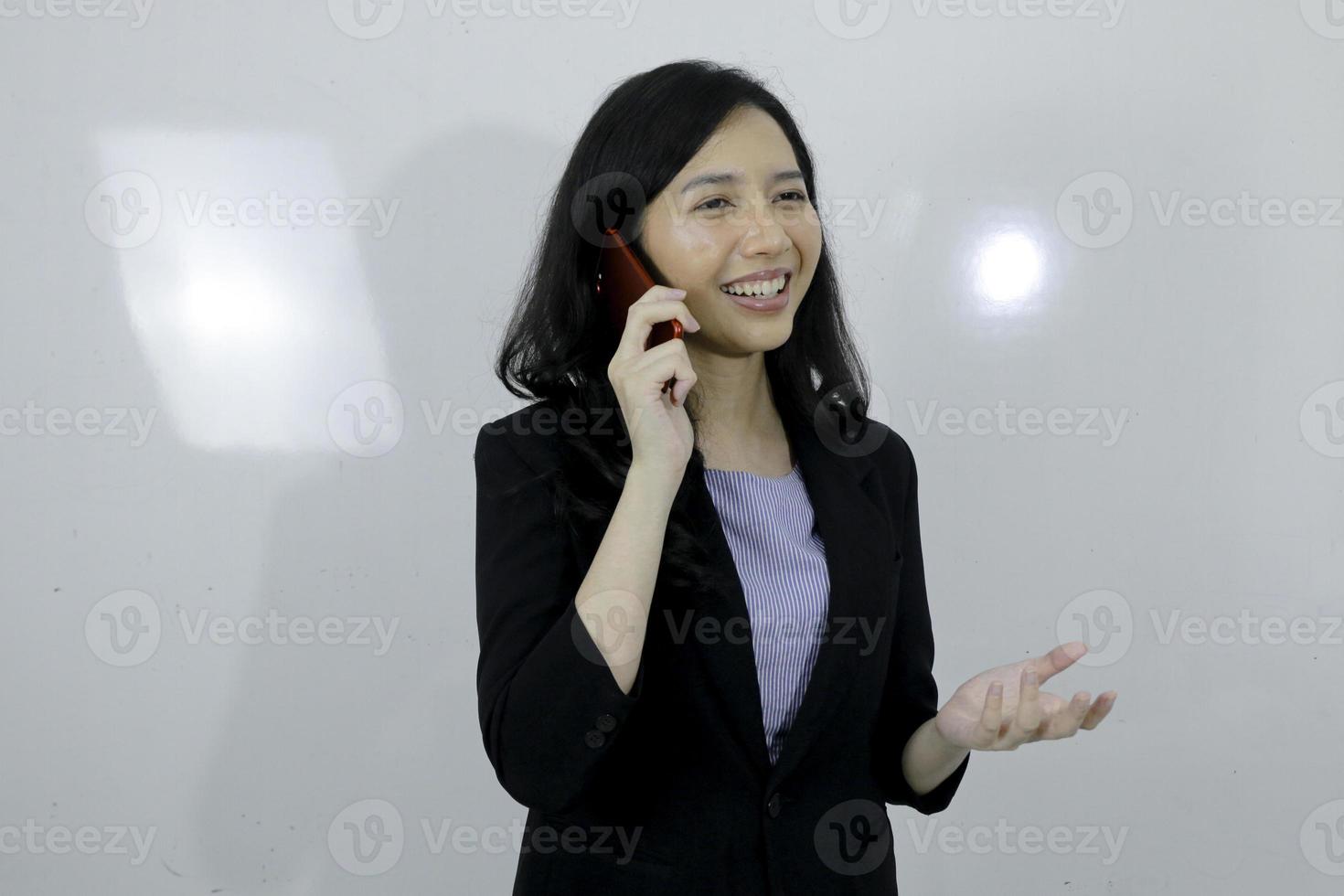 jovem asiática de negócios está feliz usando um laptop e falando no telefone foto