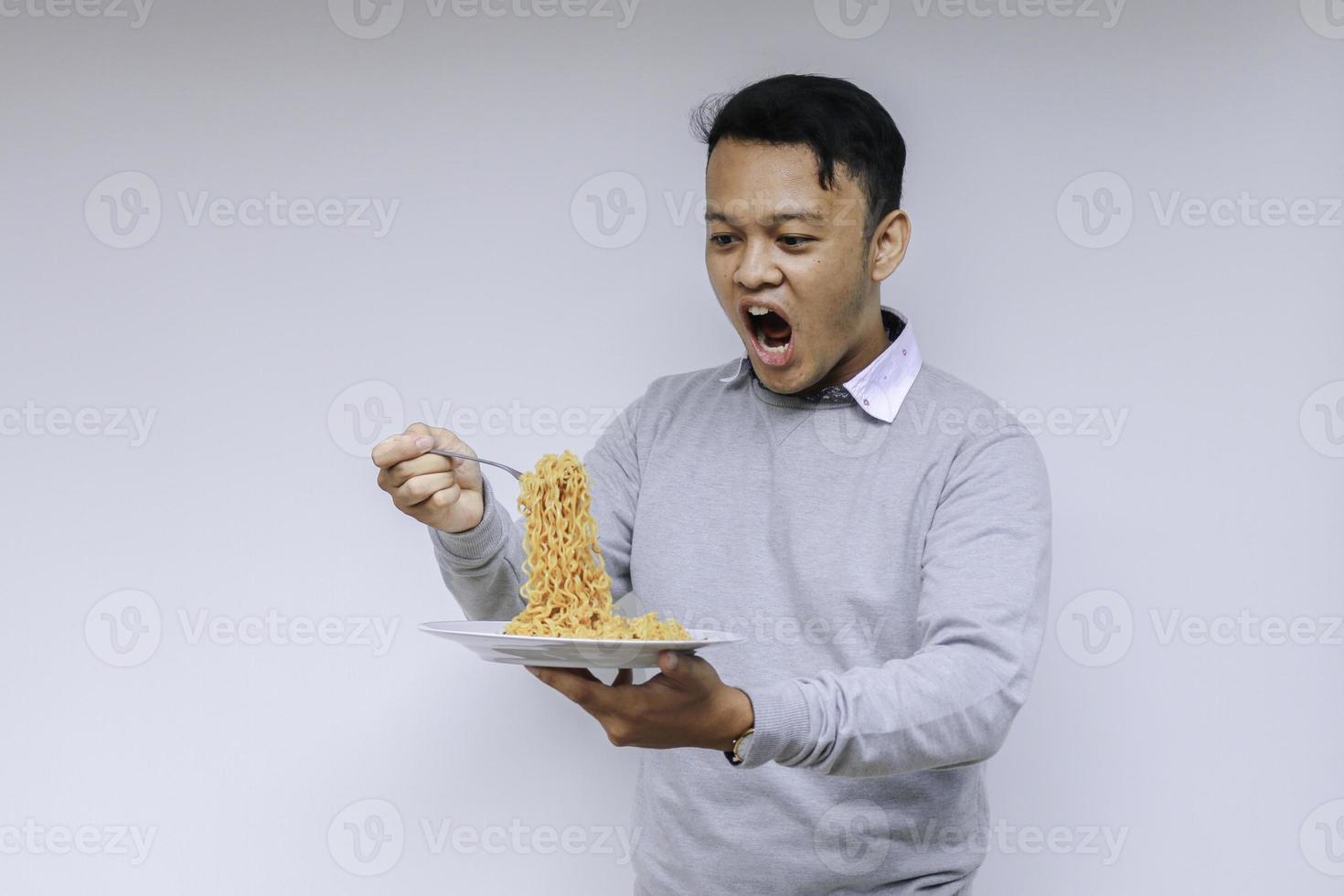 retrato de choque e uau jovem asiático gosta de macarrão. comendo o conceito de almoço. foto