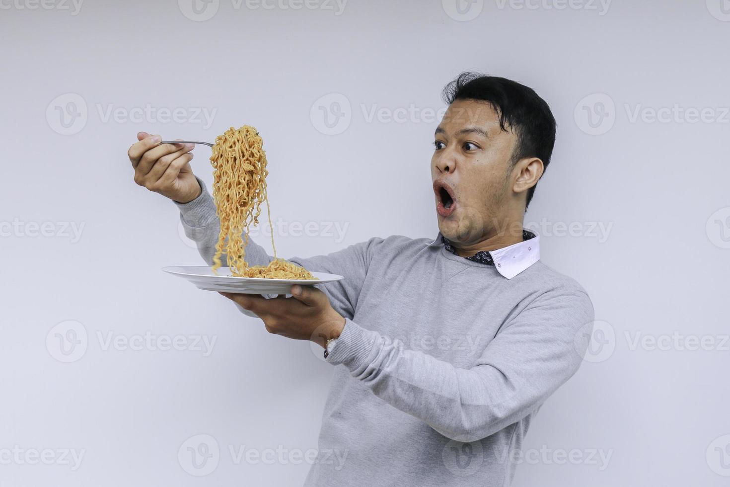 retrato de choque e uau jovem asiático gosta de macarrão. comendo o conceito de almoço. foto