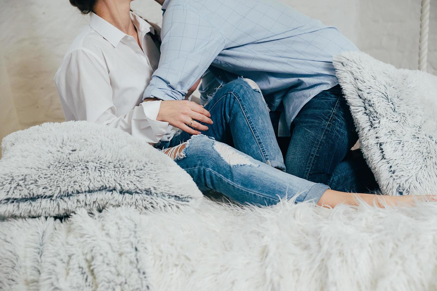 um jovem casal de jeans e camisas na cama foto