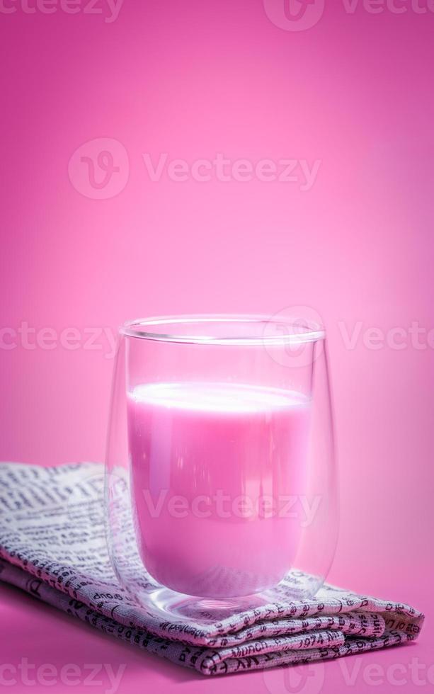 conceito de bebida de verão. leite de morango rosa com espuma de leite em vidro transparente no fundo rosa. foto