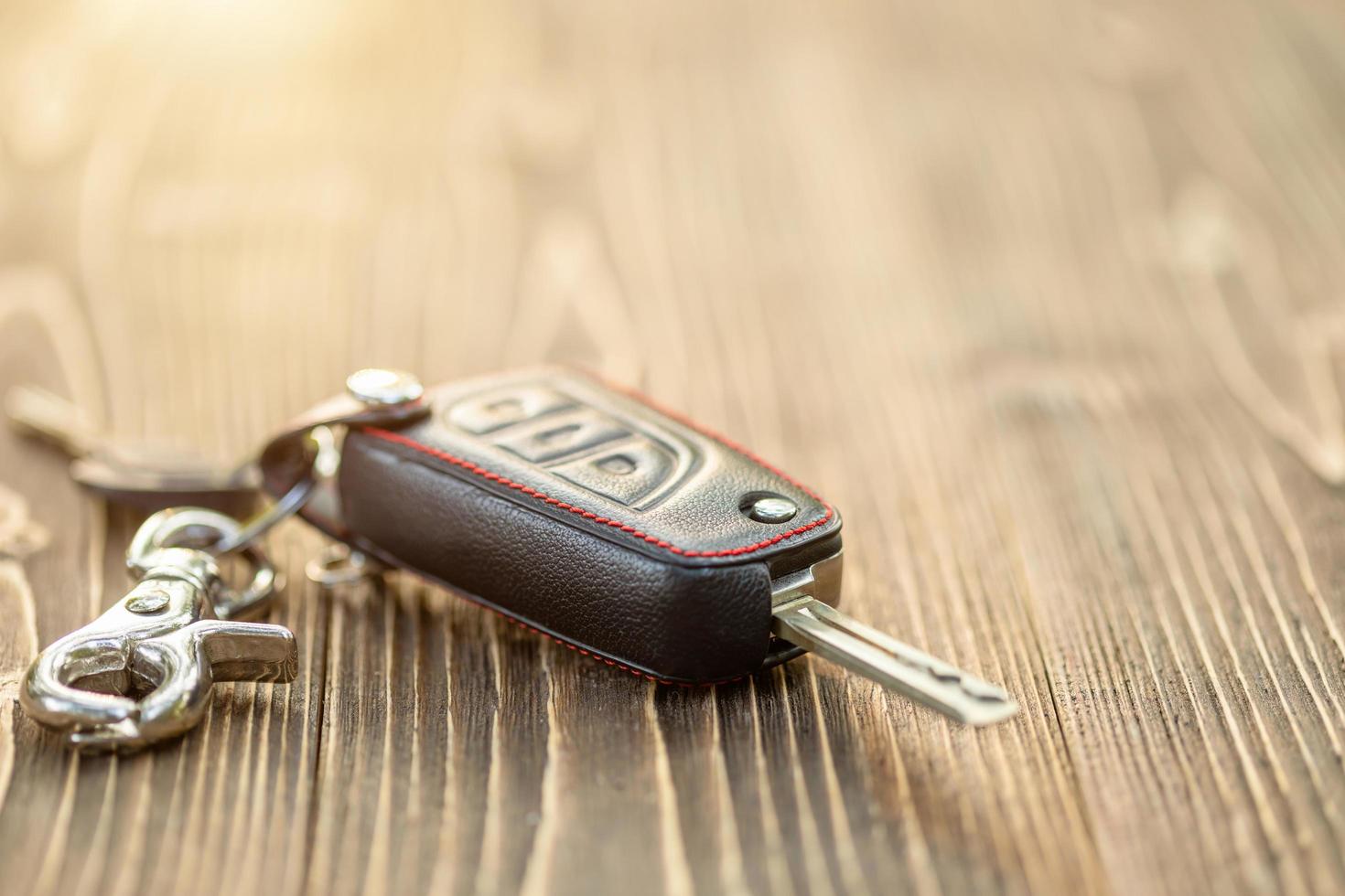 novas chaves de carro com capa de couro preta na mesa de madeira foto