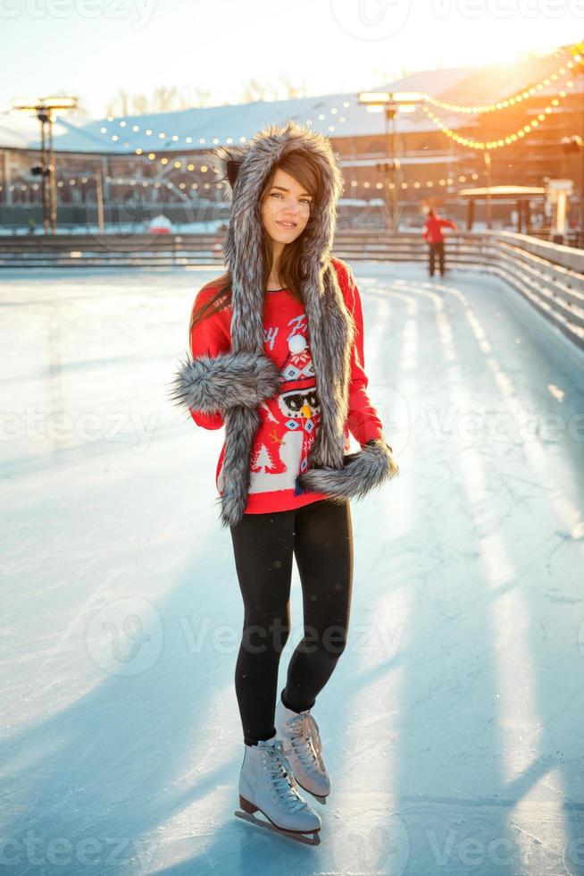 jovem mulher feliz no chapéu patinar no gelo na rua foto