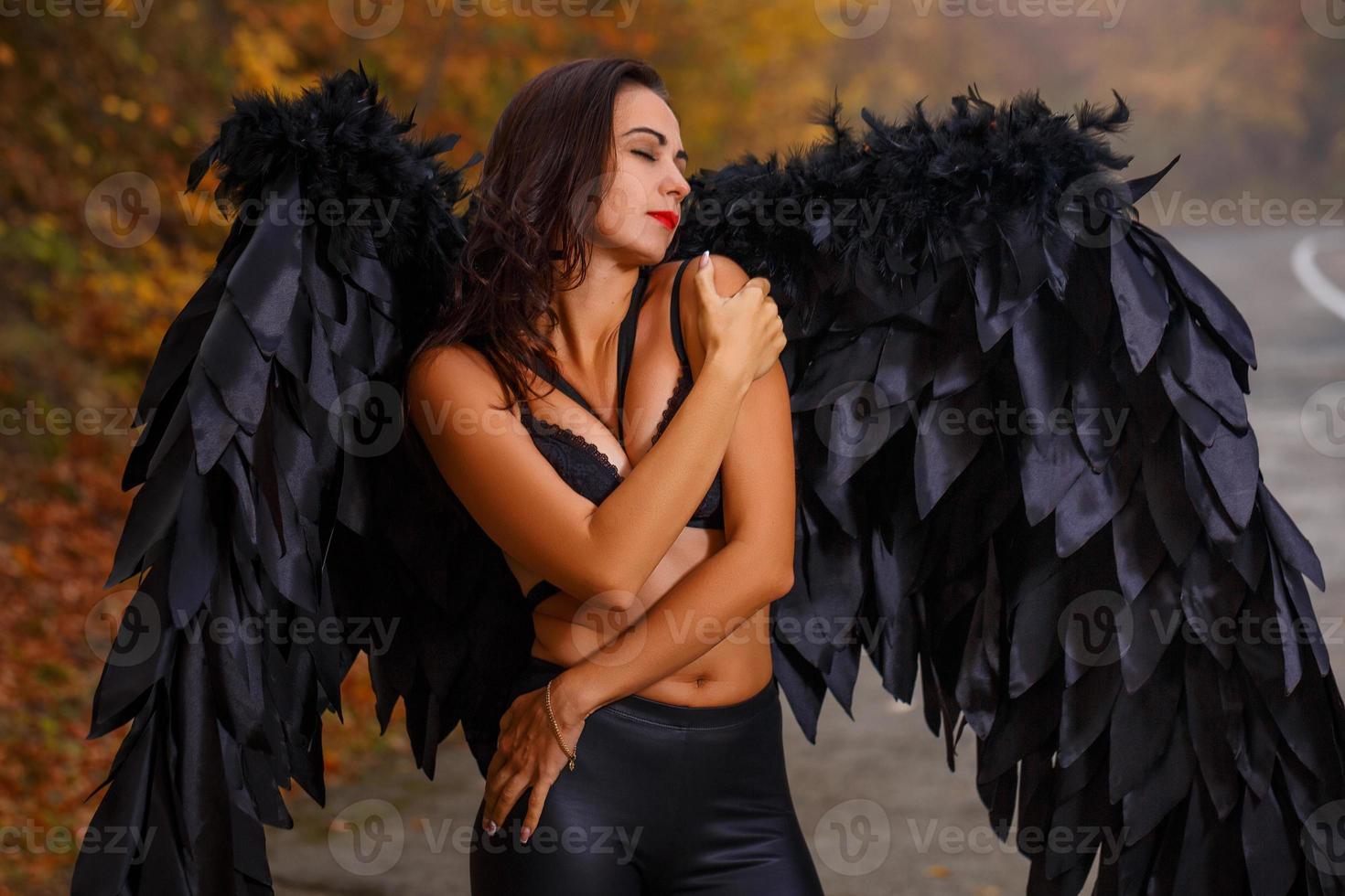 linda mulher com asas negras na floresta de outono foto