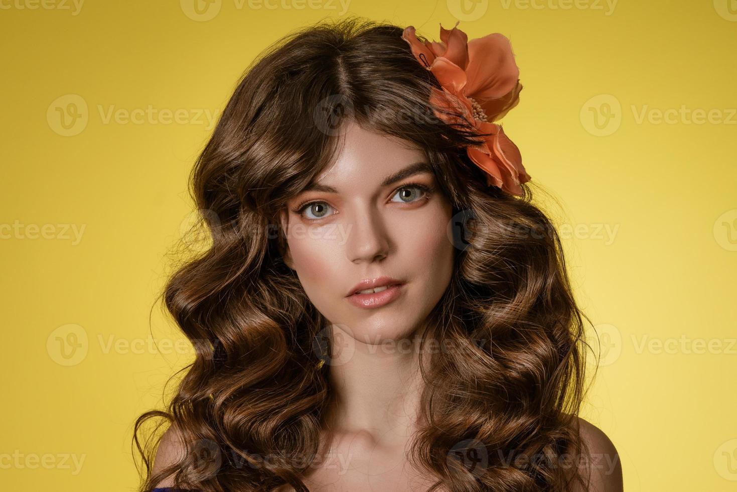 retrato de close-up de uma jovem em fundo amarelo com flor no cabelo foto