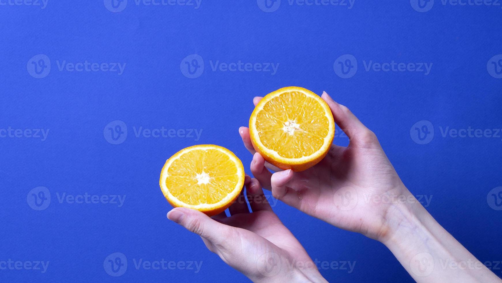 mão de uma mulher segurando uma laranja madura cortada foto