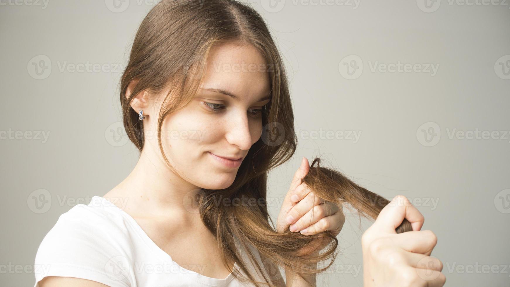 garota em um fundo cinza tem um cabelo na mão foto