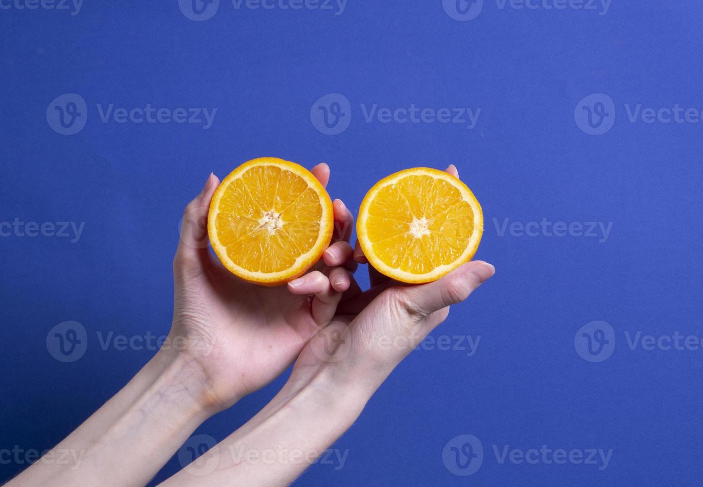 mão de uma mulher segurando uma laranja madura cortada foto