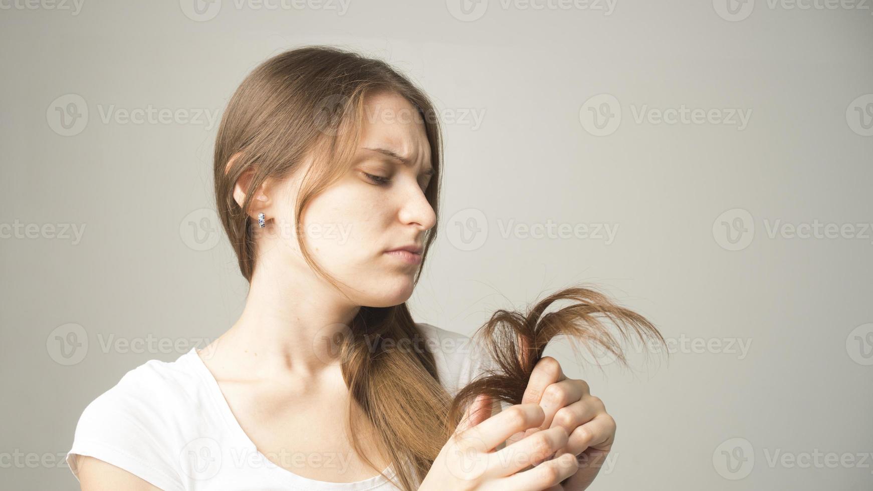 garota em um fundo cinza tem um cabelo na mão foto