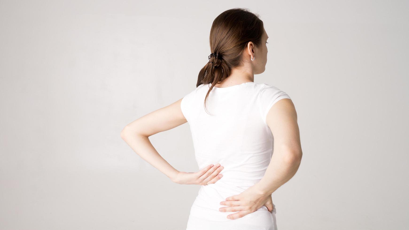 atraente adolescente sofre de dor nas costas. tudo em fundo branco foto