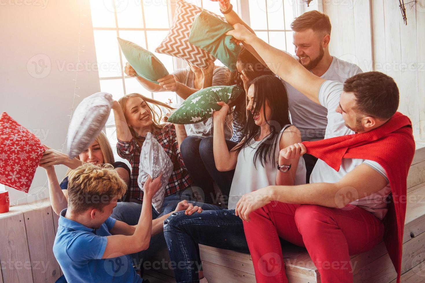 loucos jovens melhores amigos lutando contra travesseiros em casa. grupo de pessoas de raça mista. entretenimento de conceito e estilo de vida foto