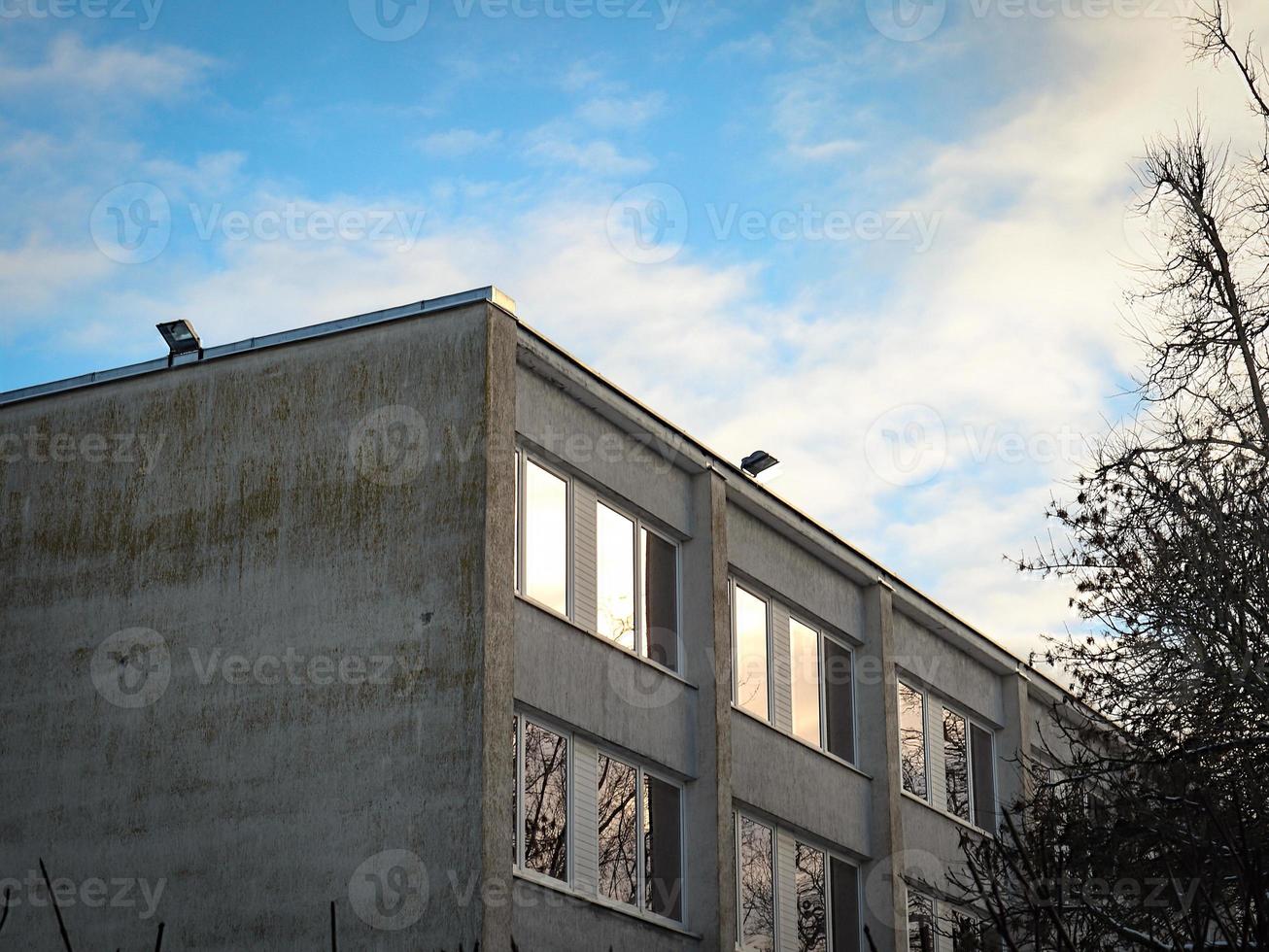 canto de construção de parede de tijolo branco velho com janelas quadradas no fundo do céu foto