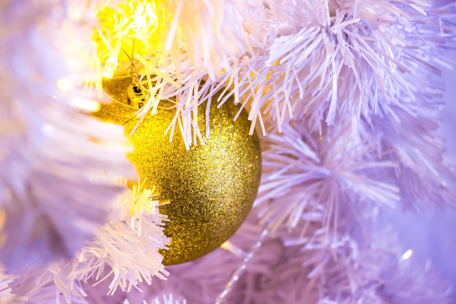 closeup de árvore de Natal branca com enfeites de suspensão de bugiganga dourada com bokeh. foto