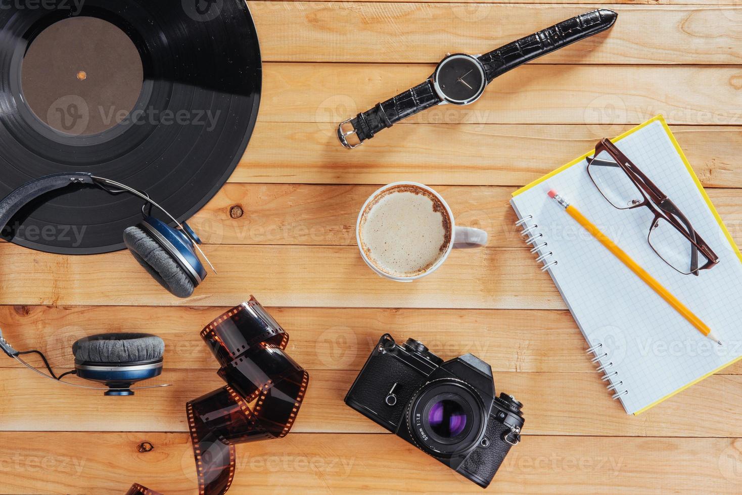 a velha câmera de filme e rolo de filme e caderno com lápis em um fundo de madeira foto