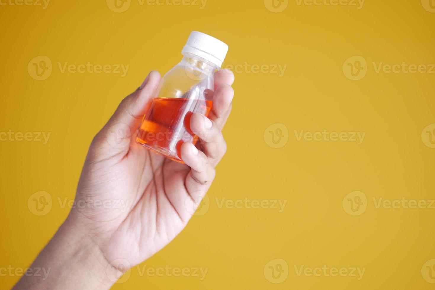 segurando a garrafa com remédio líquido em amarelo foto