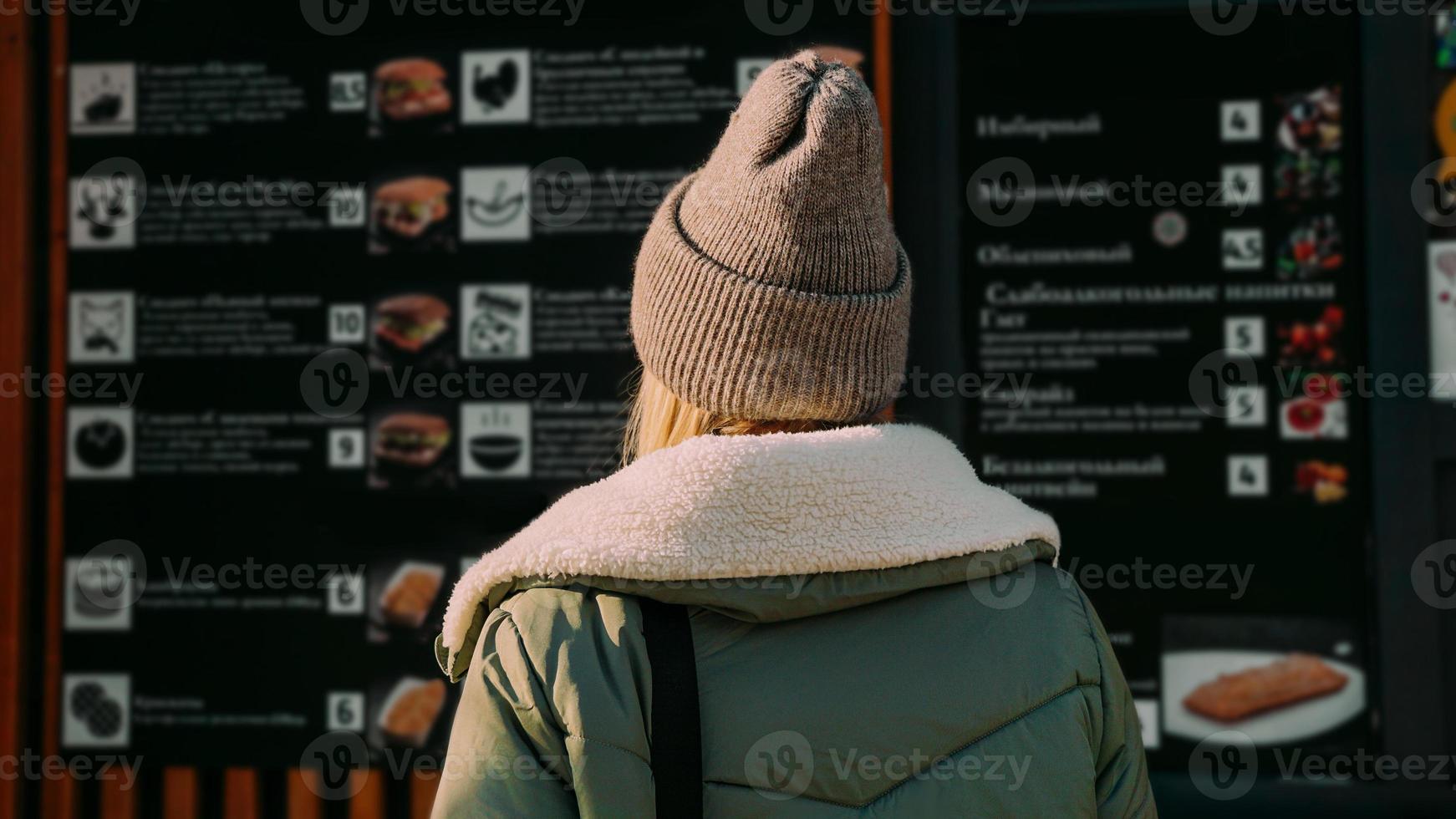 mulher em uma praça de alimentação urbana escolhe comida de um menu foto