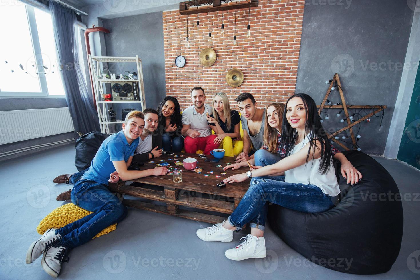 grupo de amigos criativos sentados à mesa de madeira. pessoas se divertindo jogando jogo de tabuleiro foto