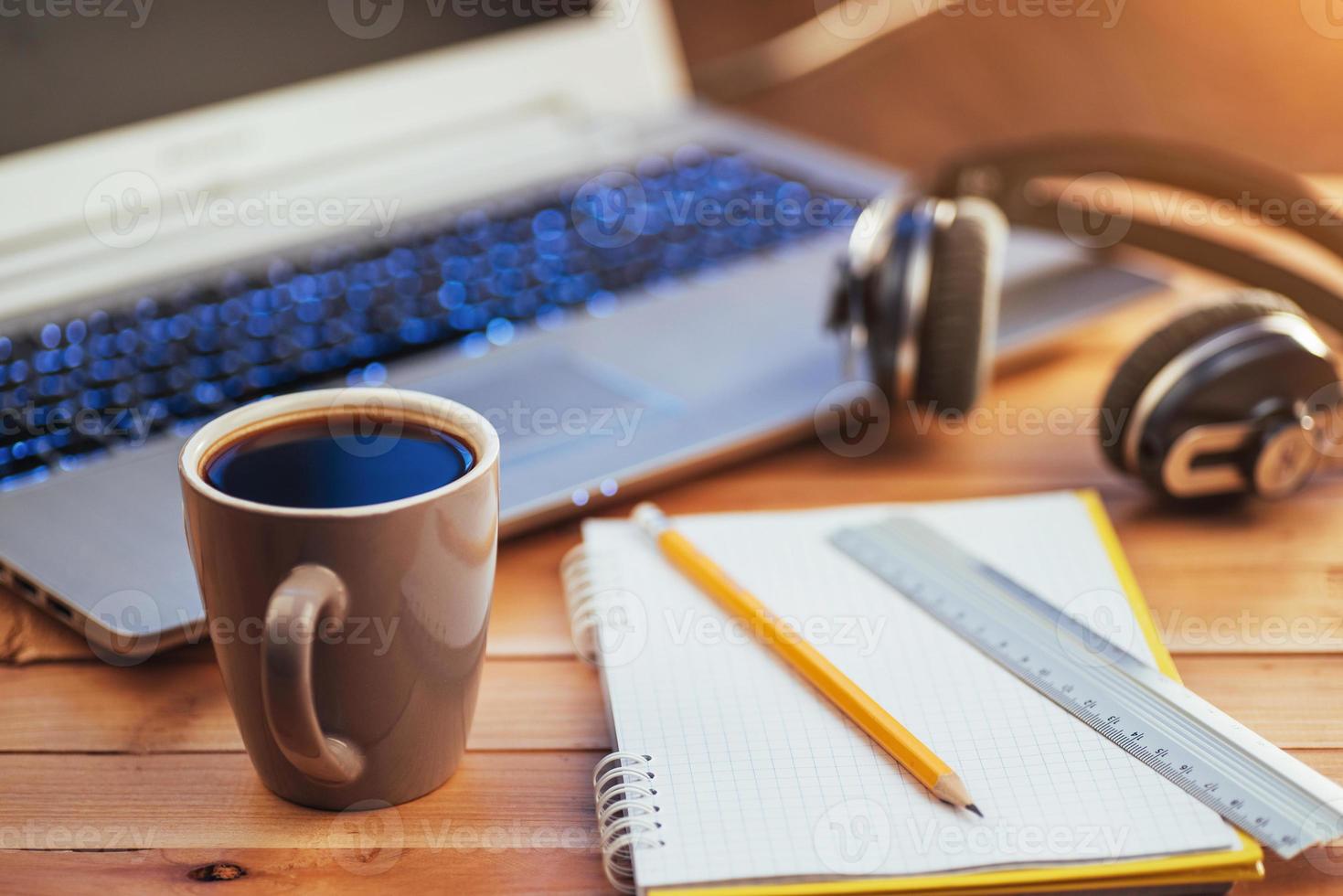 no lápis de caderno de fundo de madeira, régua e café. fones de ouvido para laptop. foto