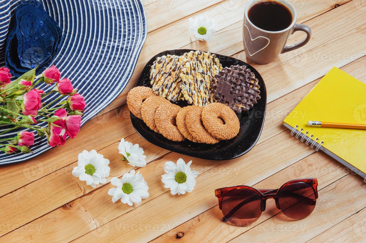 café expresso fica em uma mesa de madeira com biscoitos, bloco e lápis. foto