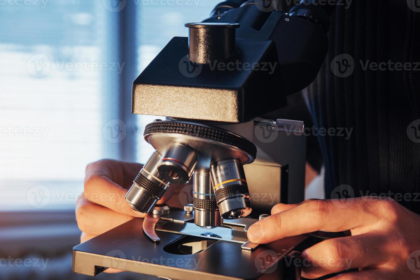 close-up de mãos de cientista com microscópio, examinando amostras. foto