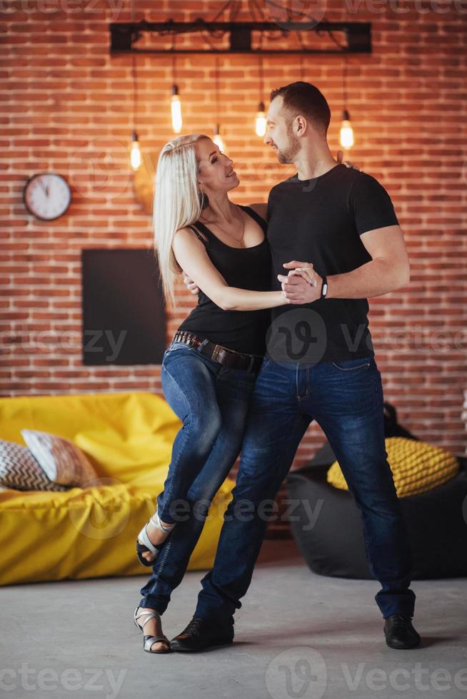 jovem casal dançando música latina bachata, merengue, salsa. duas poses de elegância no café com paredes de tijolos foto