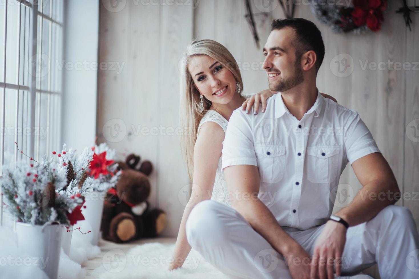 casal jovem feliz no natal, belos presentes e árvore ao fundo foto