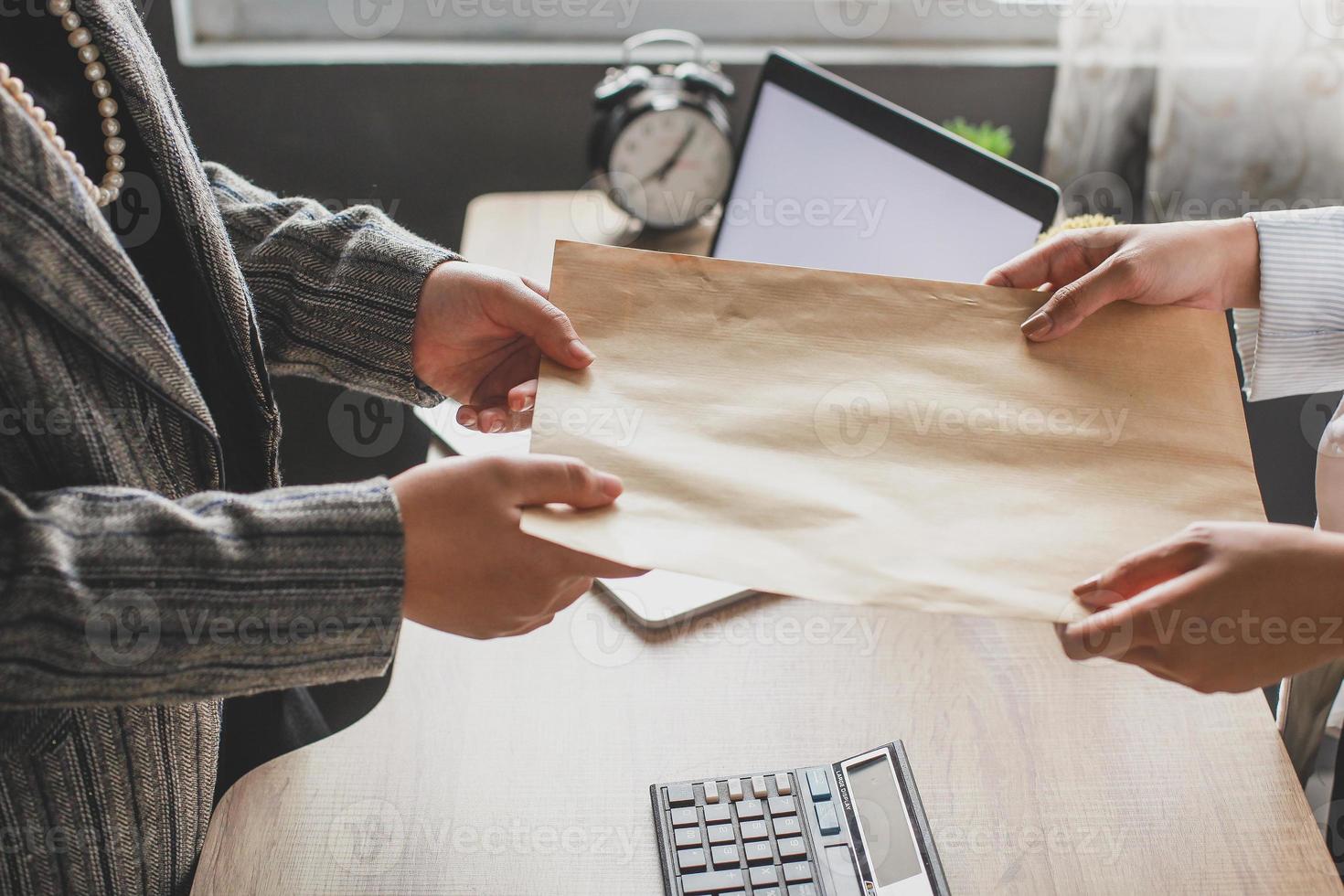 mão de mulher de negócios dando envelope para colega no escritório moderno. promoção, conceito de rh, conceito de desemprego, à procura de emprego, envelope com mensagem de oferta de emprego foto