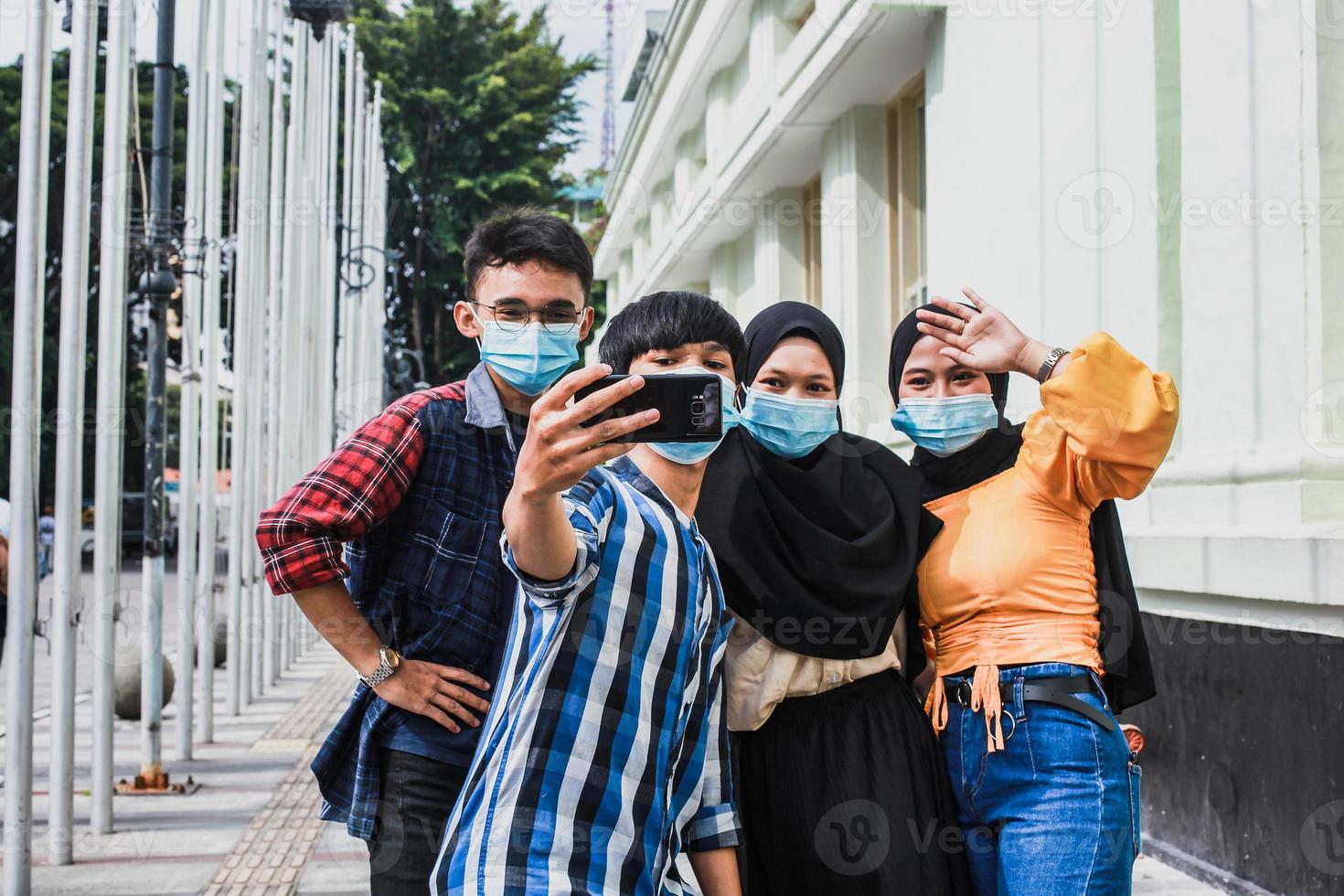 amigos com máscara de segurança protetora se divertindo tirando selfies durante a pandemia de coronavírus no verão. foto