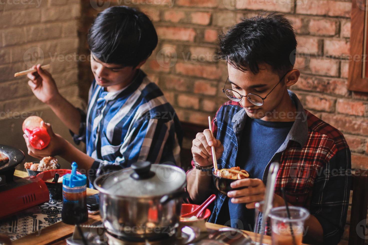 dois asiáticos comendo na festa de churrasco. comida, pessoas e conceito de tempo para a família. foto