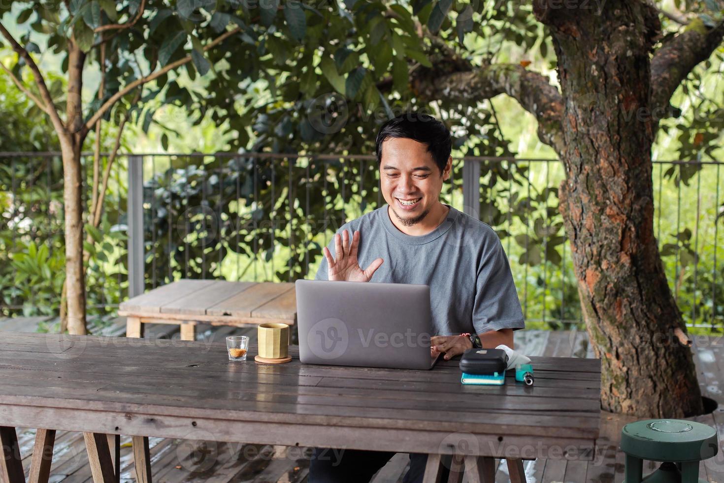 homem sentado e conversando em reunião online através de um laptop foto