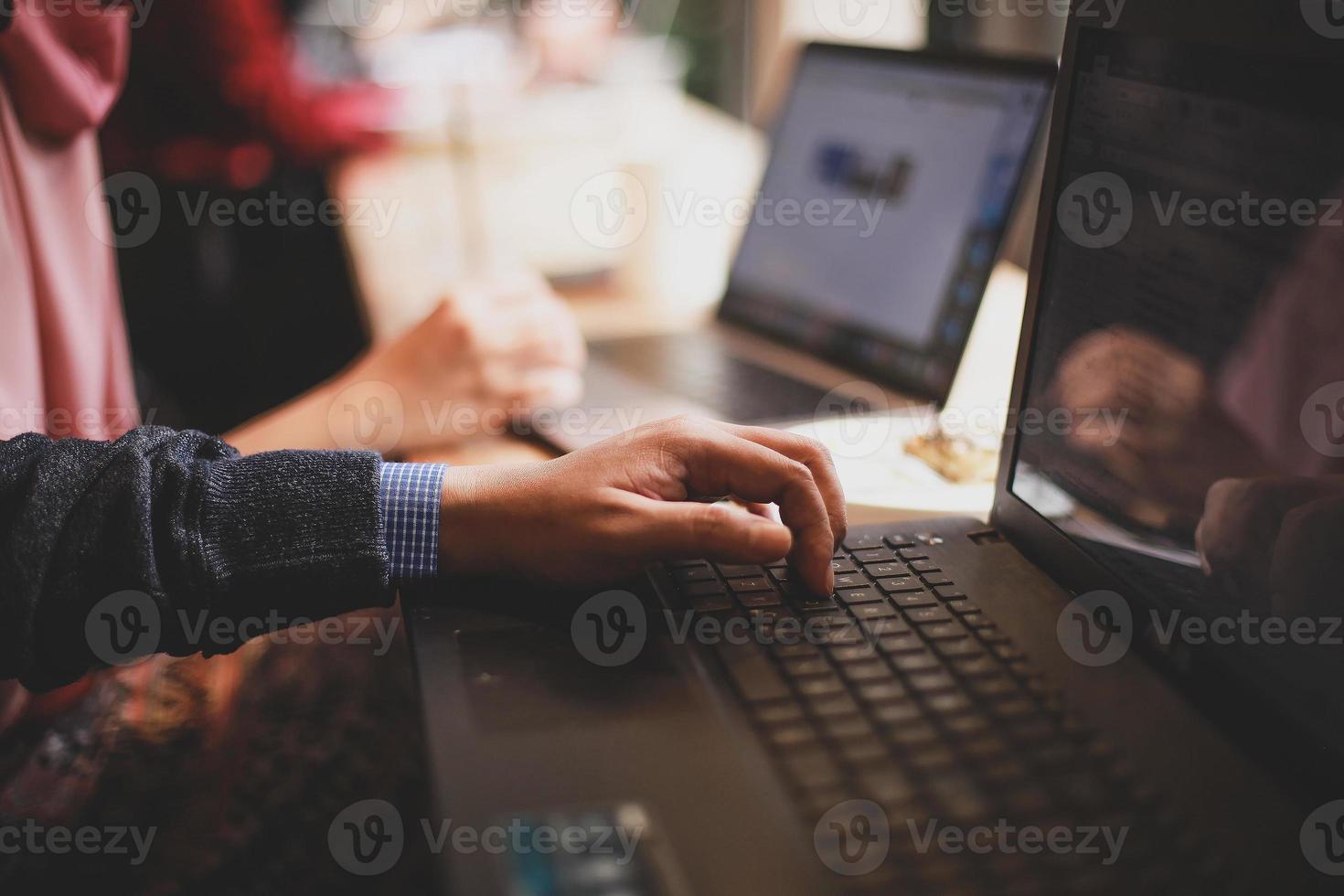 grupo de pessoas digitando no teclado laptop com fundo desfocado foto