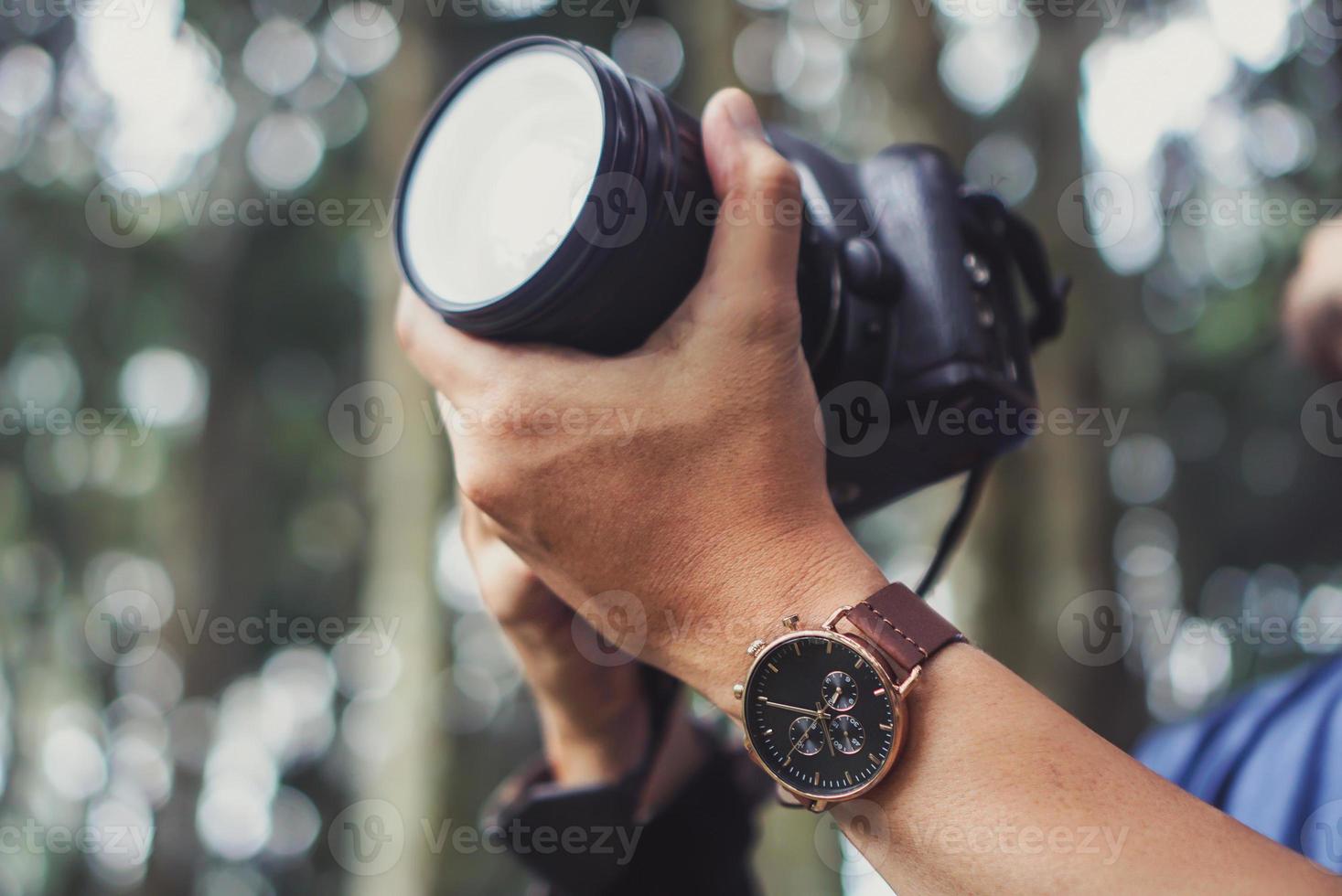 mão do fotógrafo segurando uma câmera dslr foto