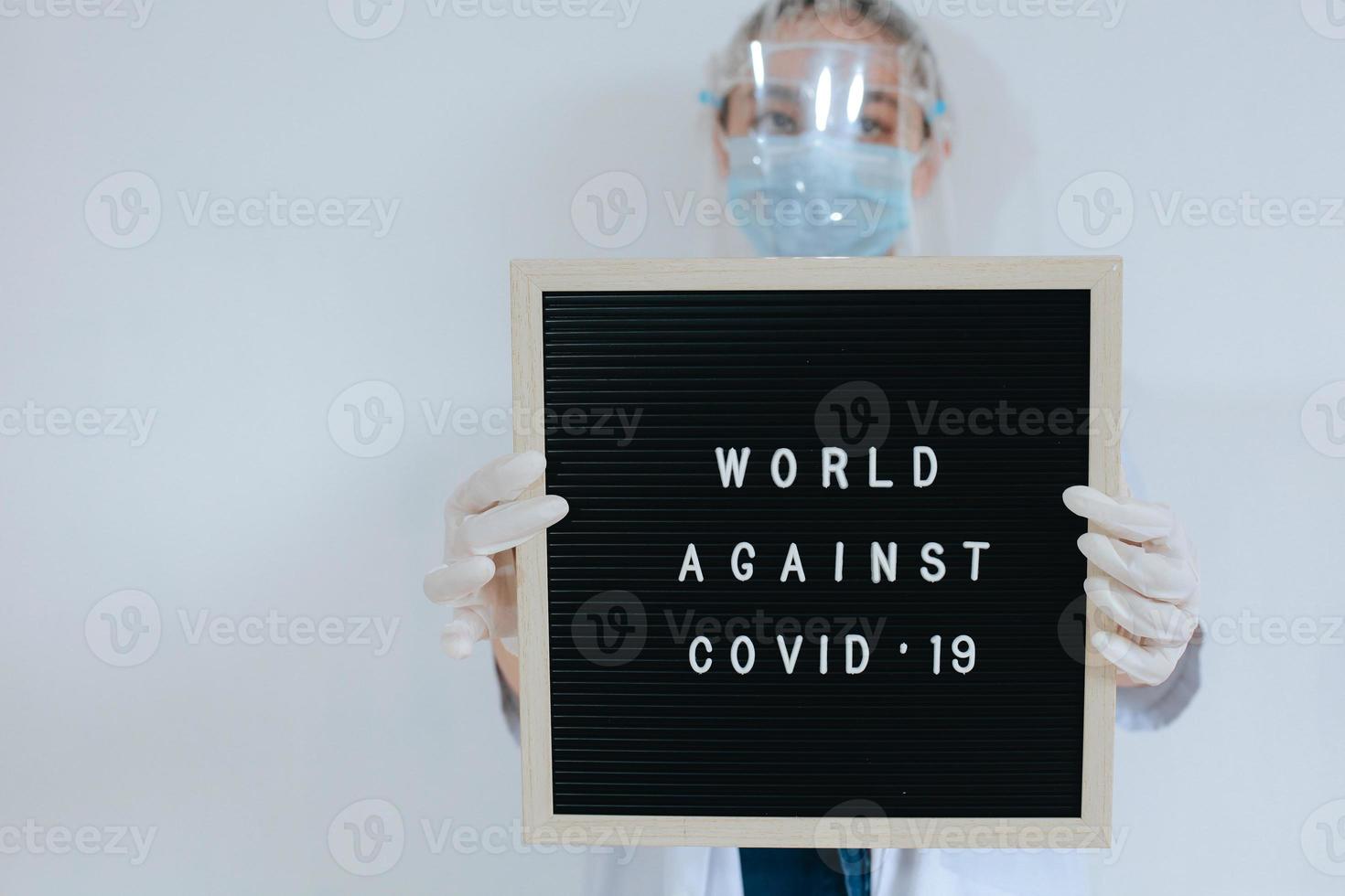 médica usando máscara protetora enquanto mantém citação no quadro de cartas diz que o mundo contra o covid 19 isolado no fundo branco. campanha contra o coronavírus foto