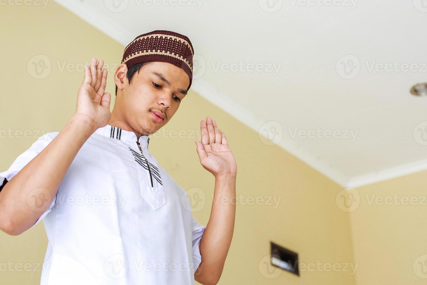 jovem muçulmano asiático fazendo salah levantando a mão, takbiratul ihram foto