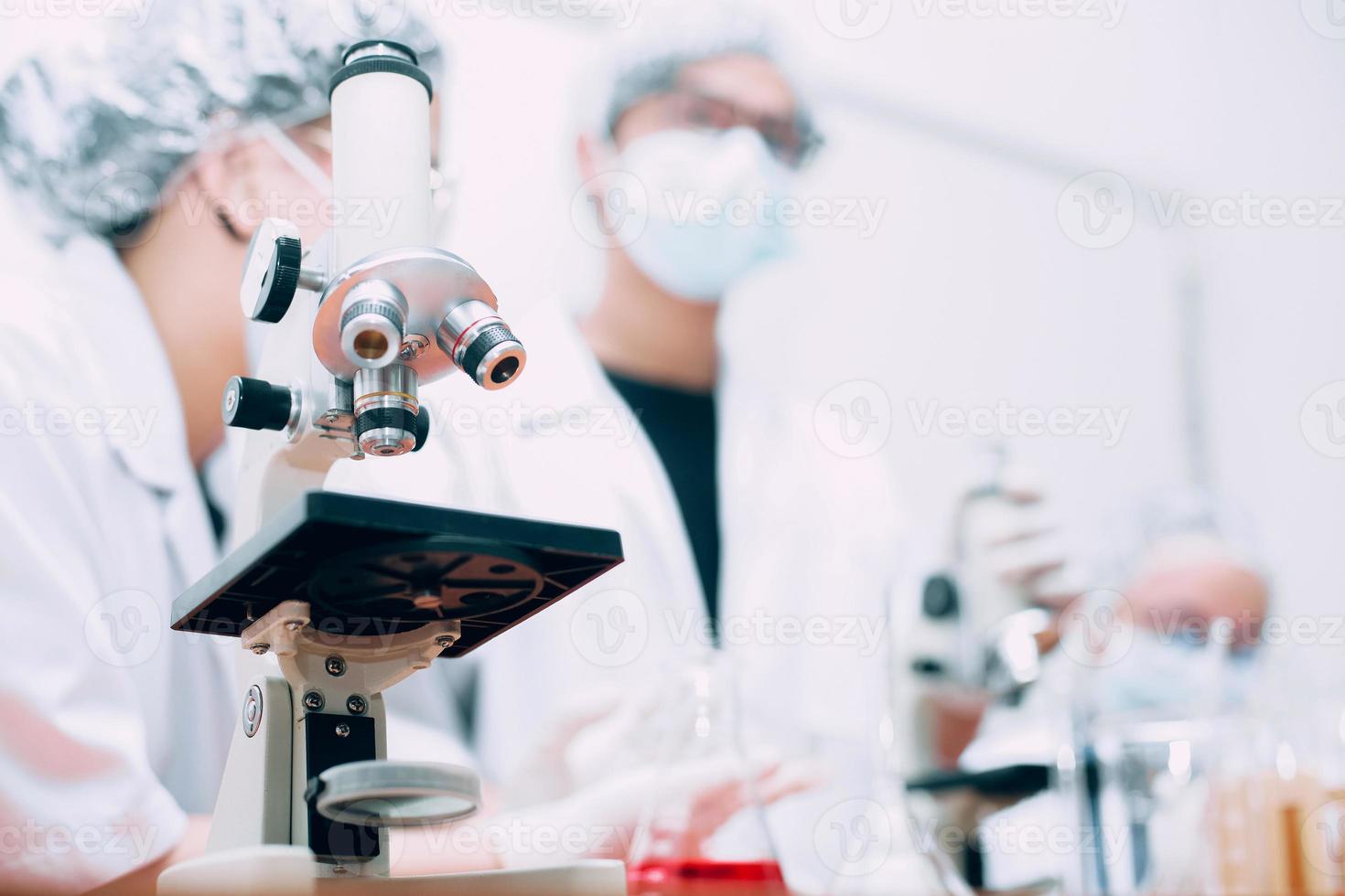 microscópio com equipe de cientistas e experimentos científicos, foco seletivo. dia nacional da ciência, dia mundial da ciência foto